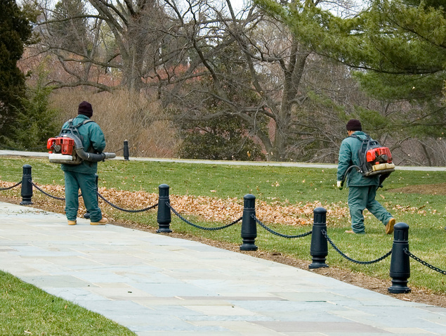 Grounds crew members clearing leaves along a cemetery path